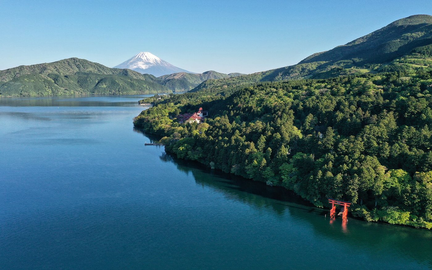The vermilion torii of Hakone Shrine standing in the shallows of Lake Ashi, with Mount Fuji behind it