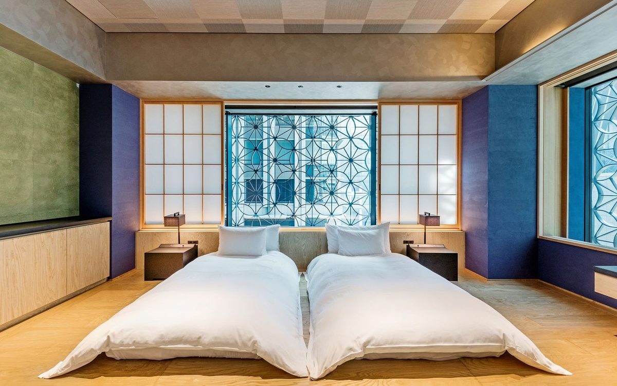A Japanese hotel room laid out as a twin: two beds on the floor, low furniture and a shoji screen