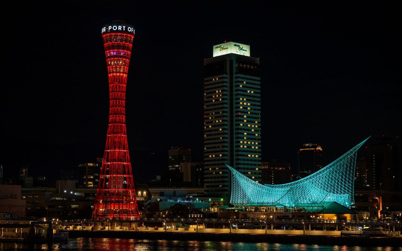 Kobe Port Tower and the Maritime Museum lit up at night, reflecting on the water