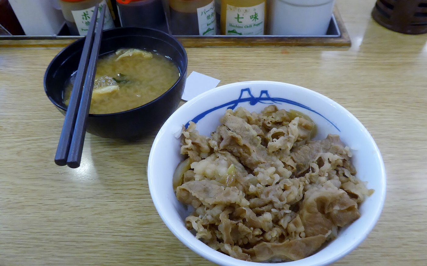 A Matsuya beef bowl of simmered beef and onion on rice beside a bowl of miso soup