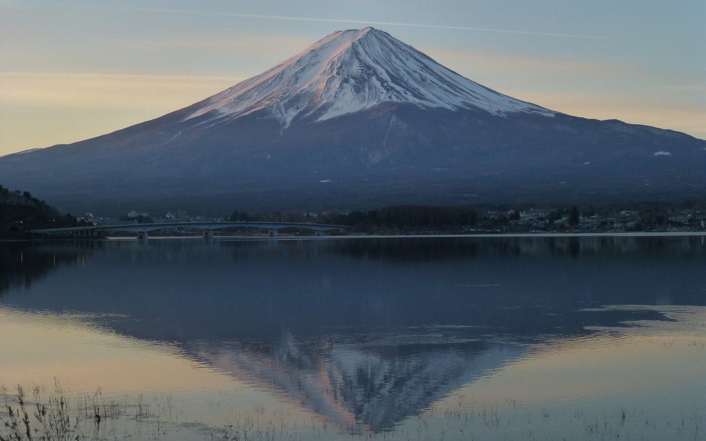 Mount Fuji mirrored in the calm water of Lake Kawaguchi at dawn