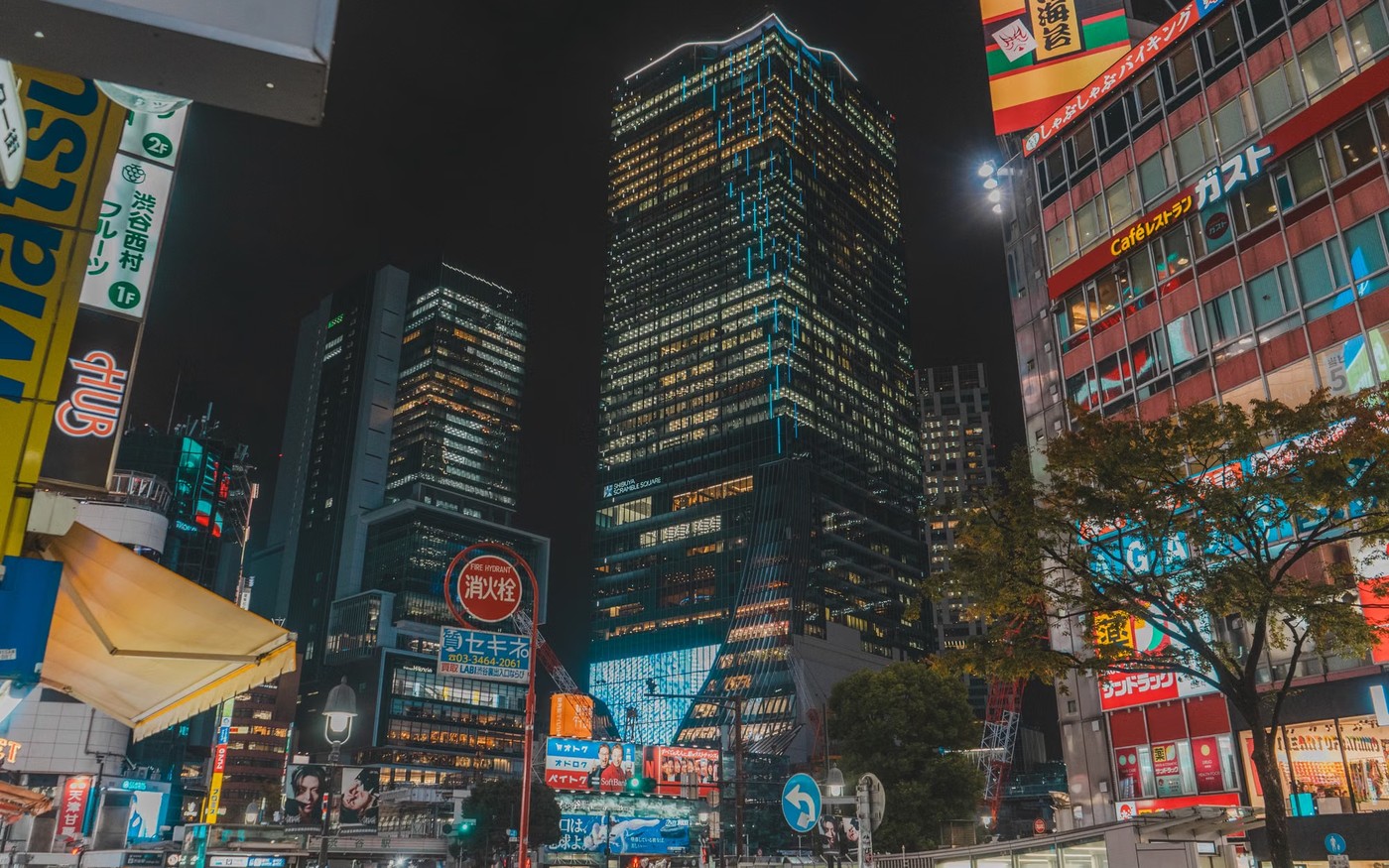 A Tokyo street at night, with shop and hotel signs above the traffic