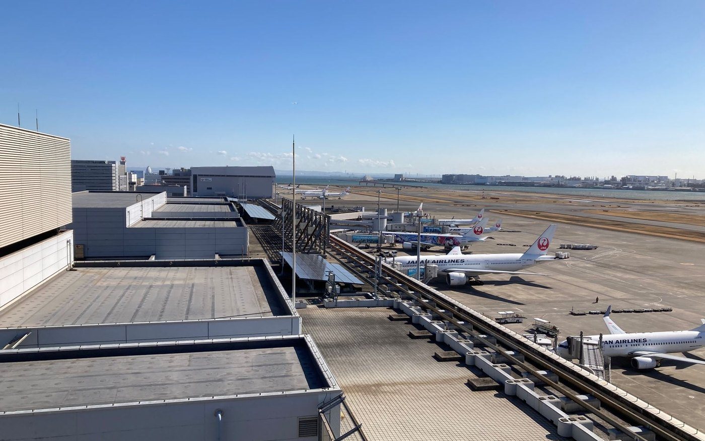 Japan Airlines aircraft parked at the terminal gates at Haneda Airport, seen from above