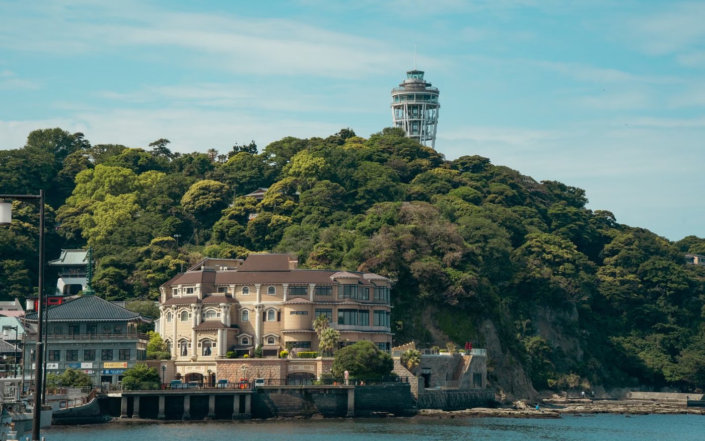 The Sea Candle observation tower on Enoshima above the trees and the water