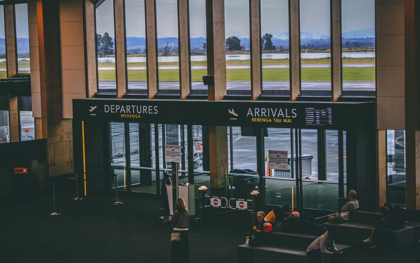 An airport terminal entrance with overhead signs reading departures and arrivals
