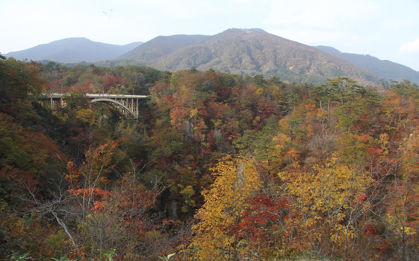 A bridge crossing a gorge between autumn-coloured mountains