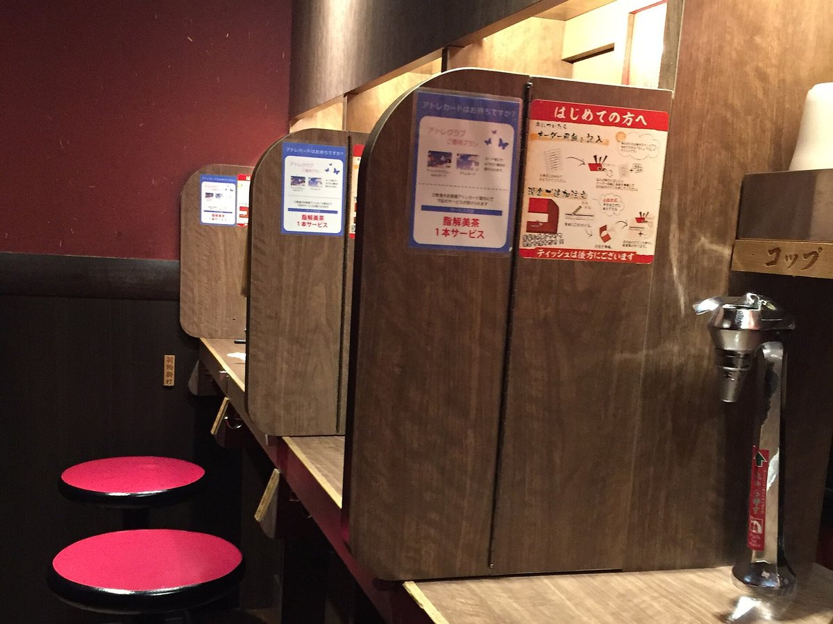 A row of partitioned ramen seats with individual compartments