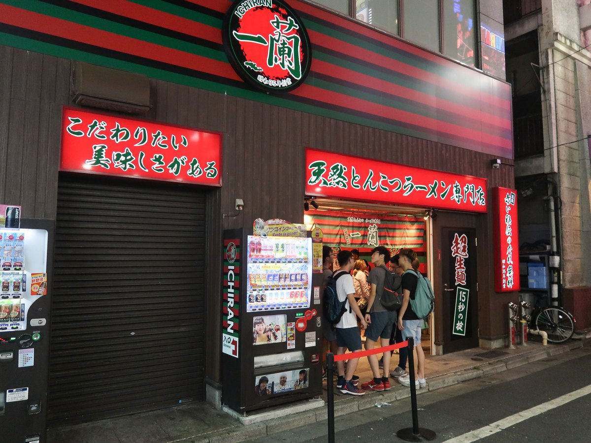 A queue of people outside a ramen shop at night