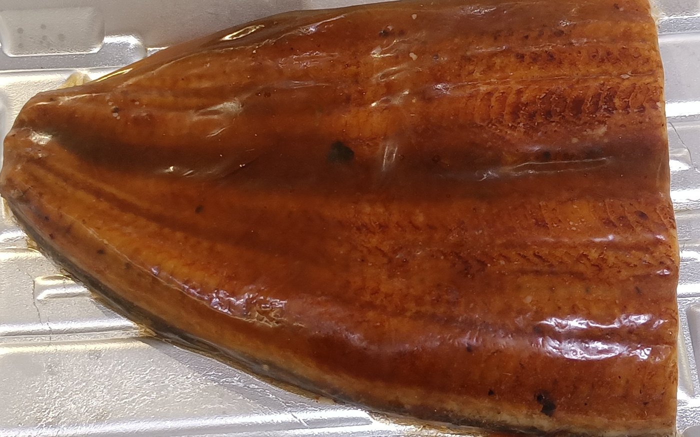 Grilled eel fillet glazed with kabayaki sauce on a tray