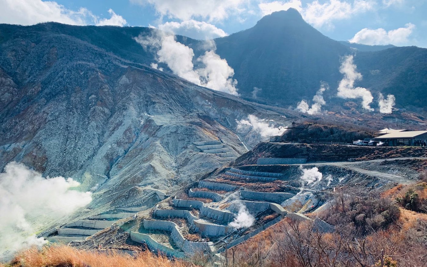 Steam rising from a volcanic valley with rough mountains behind it