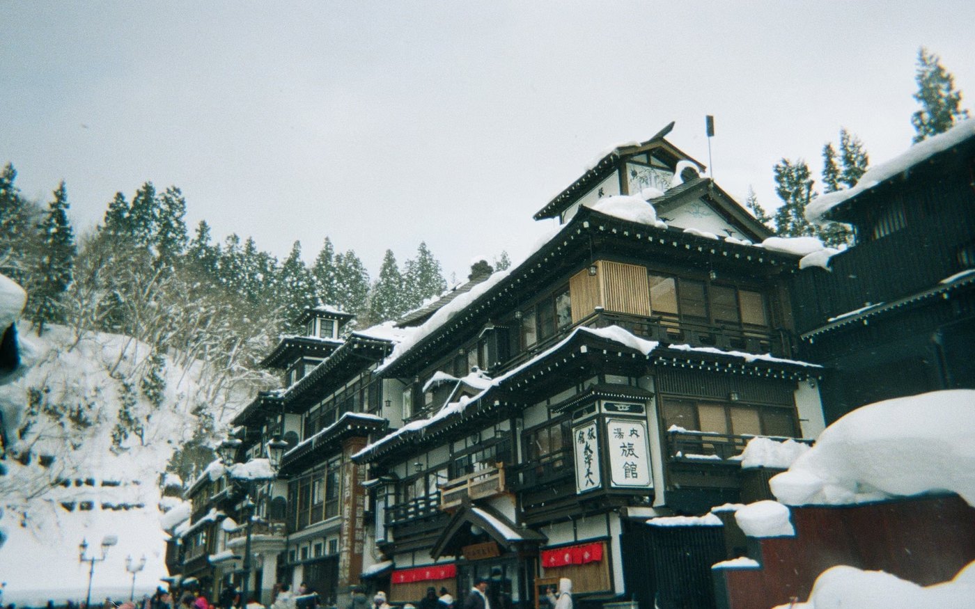 A street of wooden buildings under heavy snow in a Japanese hot spring town