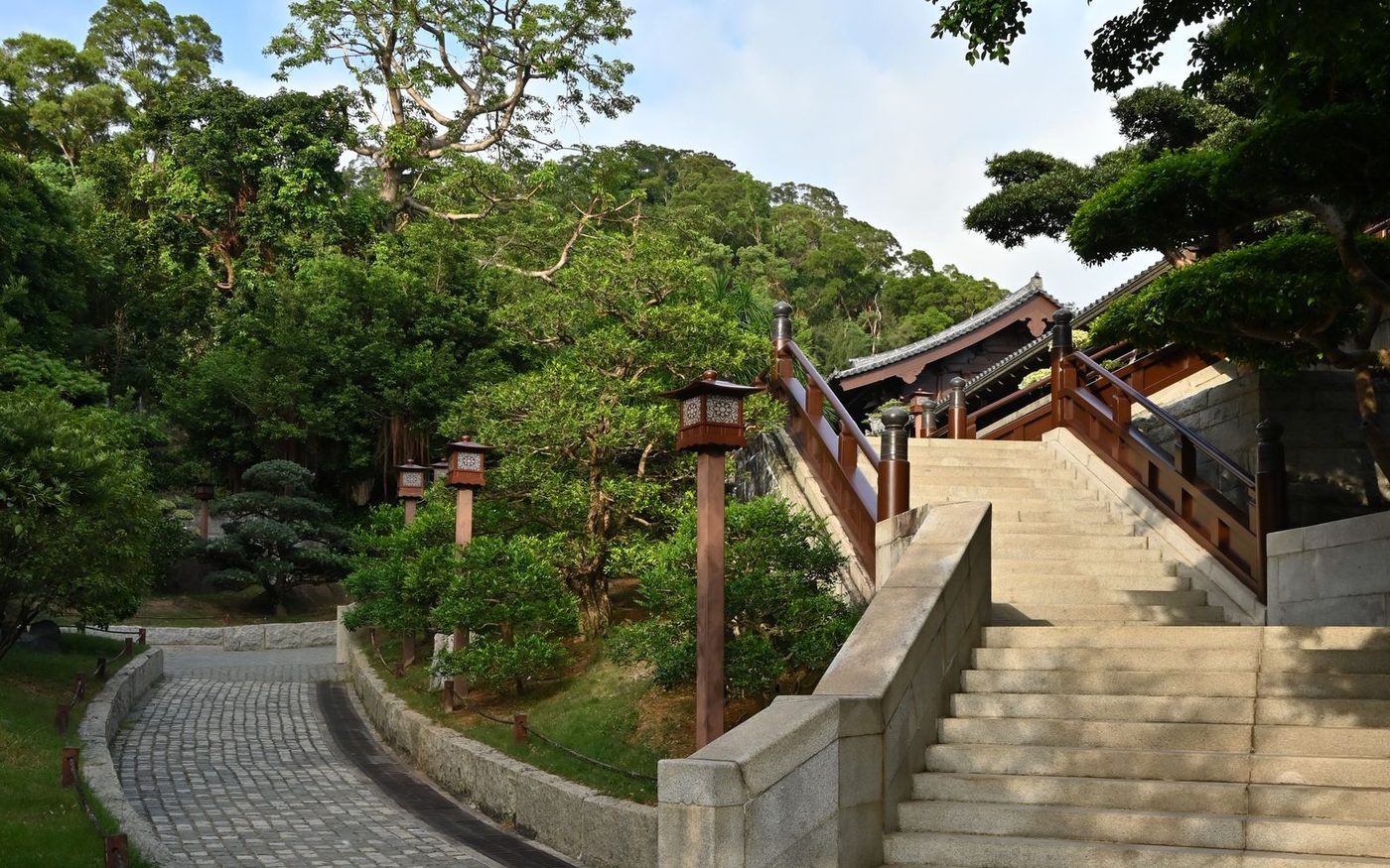 A stone-paved path with steps running between trees and stone lanterns