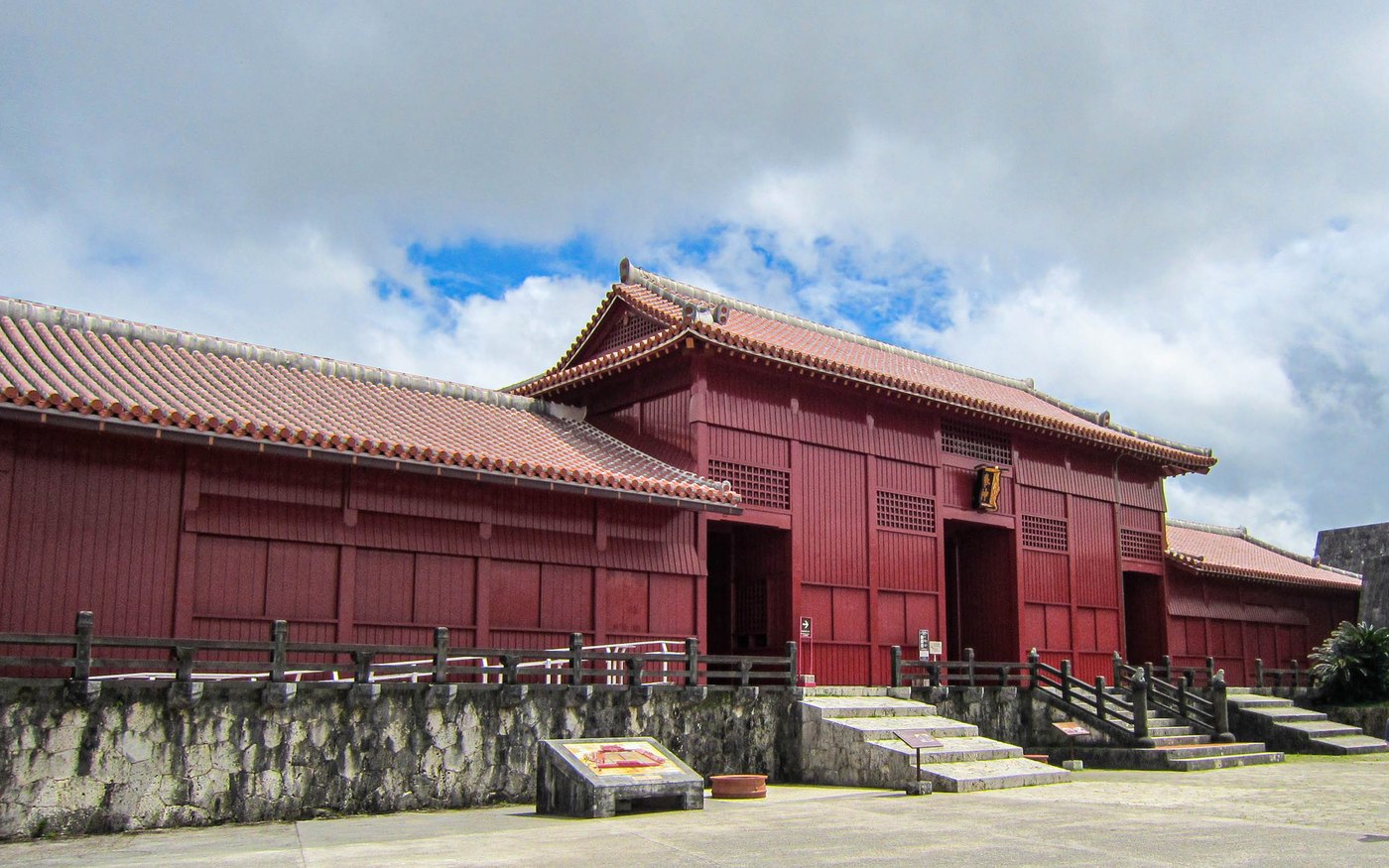 The wide red gate of Hoshinmon at Shuri Castle with stone steps and visitors in front of it