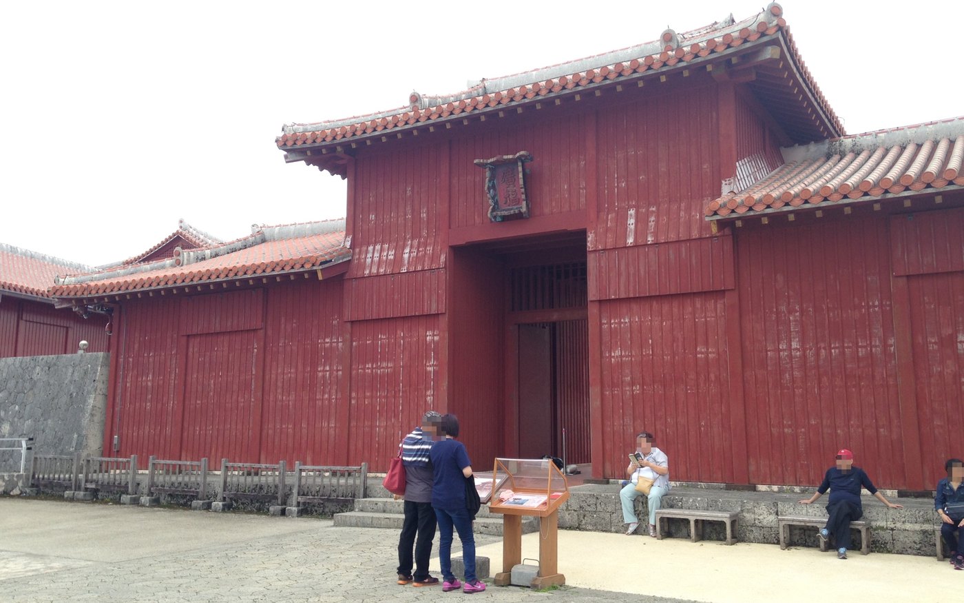 The red gate building of Kofukumon at Shuri Castle, with ticket displays and visitors in front of it