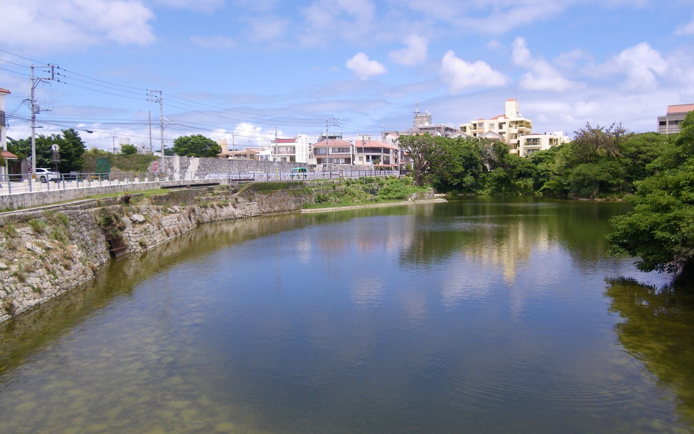 The still green water of Ryutan pond with its stone-lined banks and trees on the far side