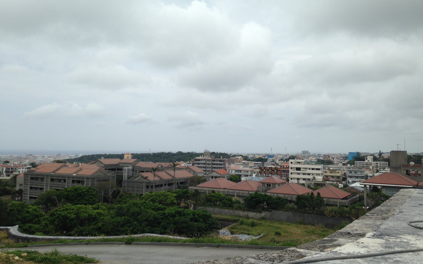 A view over the city of Naha from inside the walls of Shuri Castle, with concrete buildings and greenery below