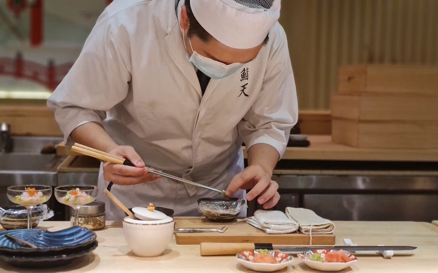 A chef preparing sashimi behind a sushi counter