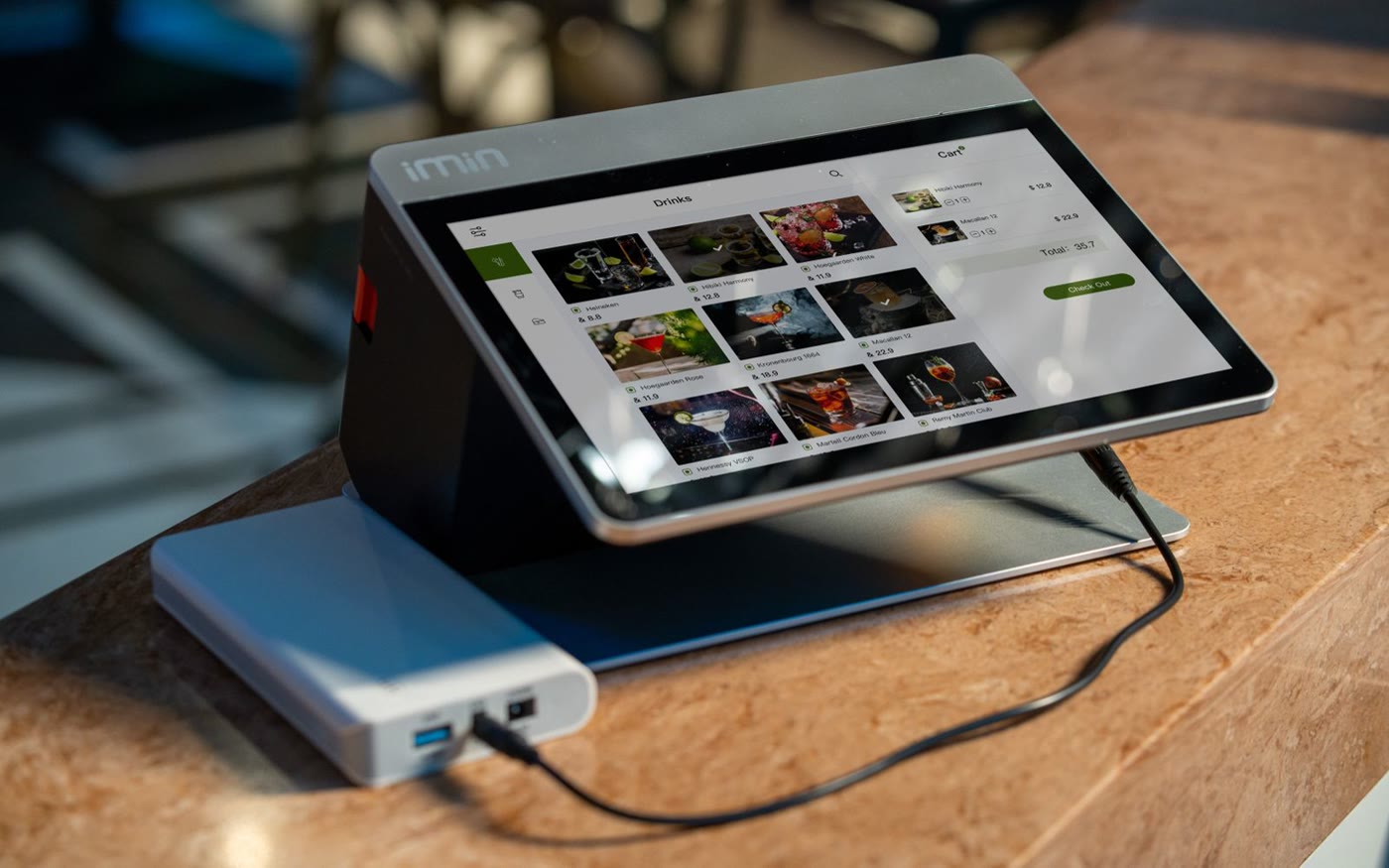 A tablet terminal on a stand at a restaurant counter, its screen showing a menu of dishes