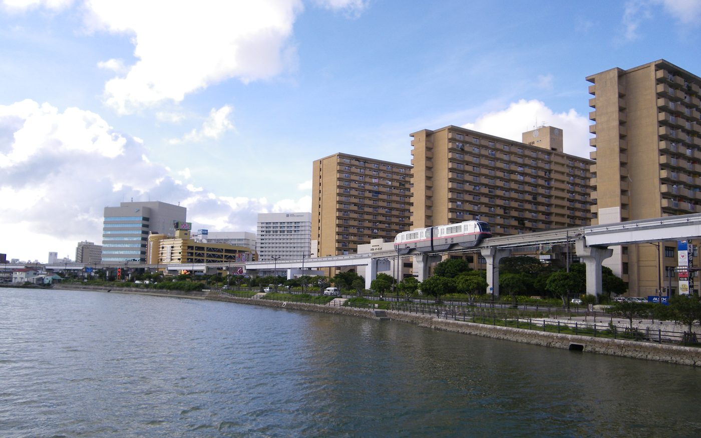A Yui Rail monorail train on its elevated track beside a river in Naha