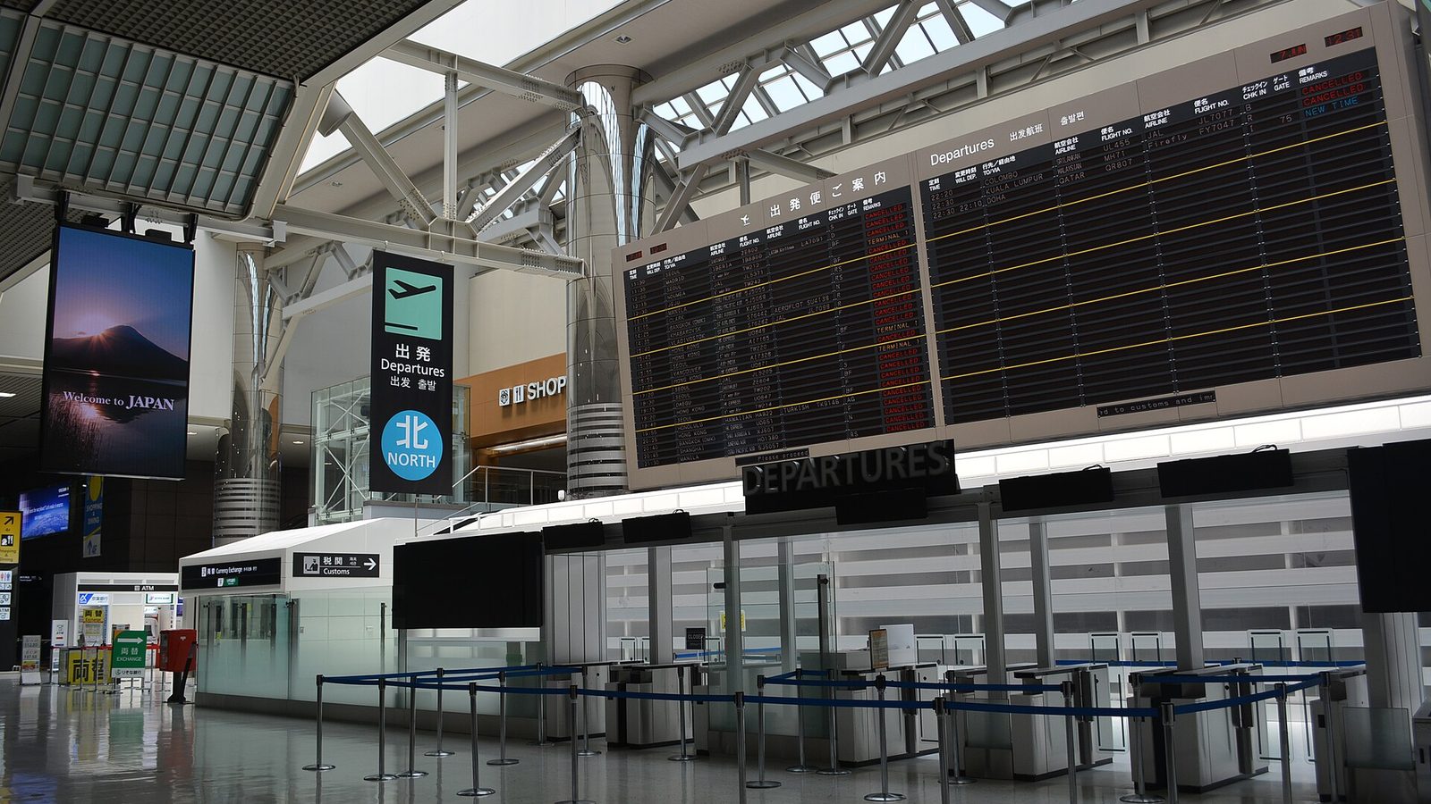 A departure hall at Narita Airport with check-in counters and a flight information board
