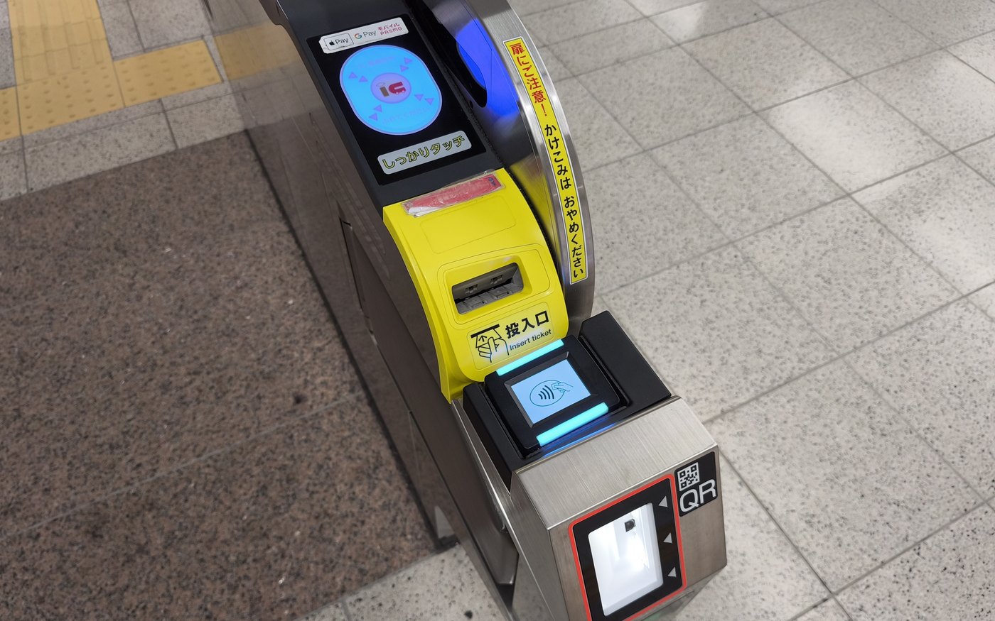 The IC reader pad on top of a Tokyo Metro ticket gate, a blue circle marked IC beside a touch-firmly sticker