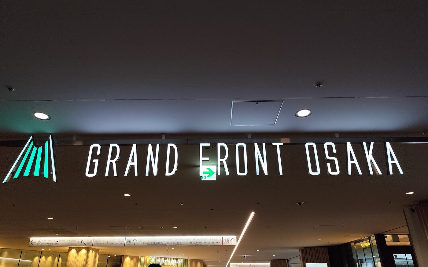 The illuminated Grand Front Osaka name sign inside the mall atrium at night
