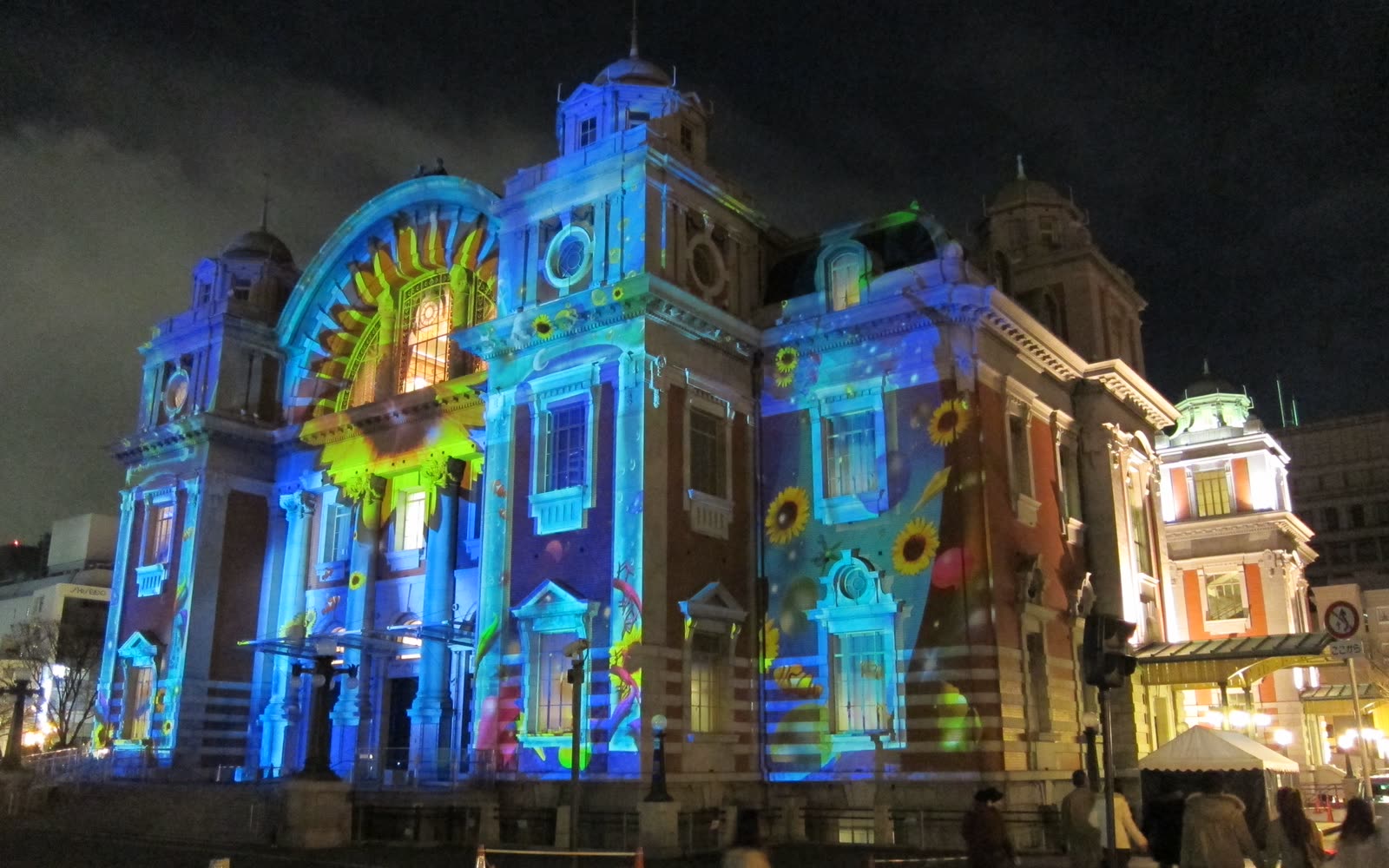Osaka City Central Public Hall at night, its facade covered in colourful projection-mapping