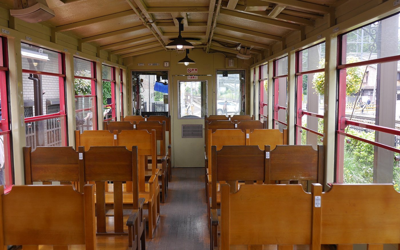 The wooden open carriage of the Sagano Romantic Train, benches down the middle and no glass