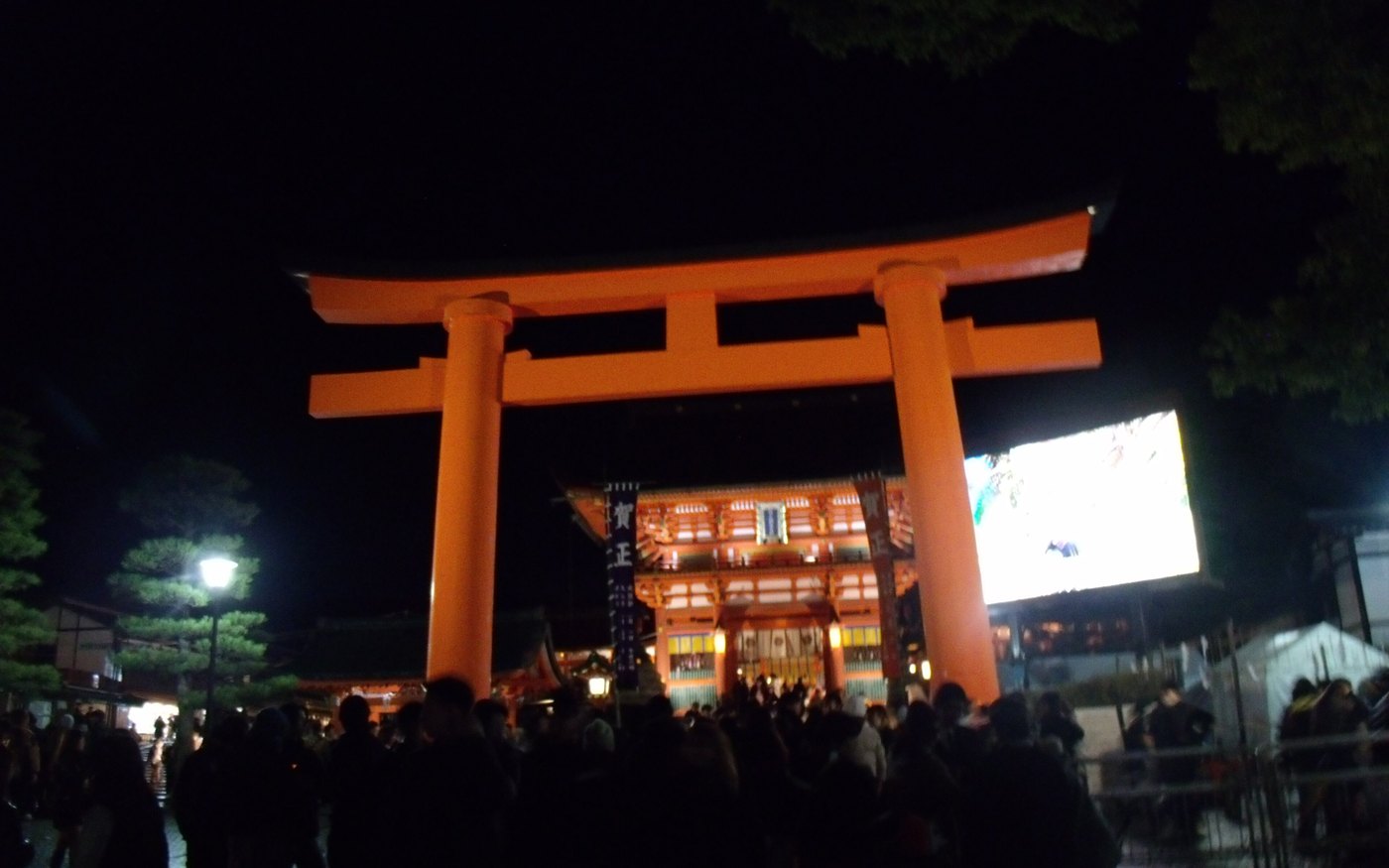 A lit torii at Fushimi Inari Taisha with a crowd beneath it on New Year's Day
