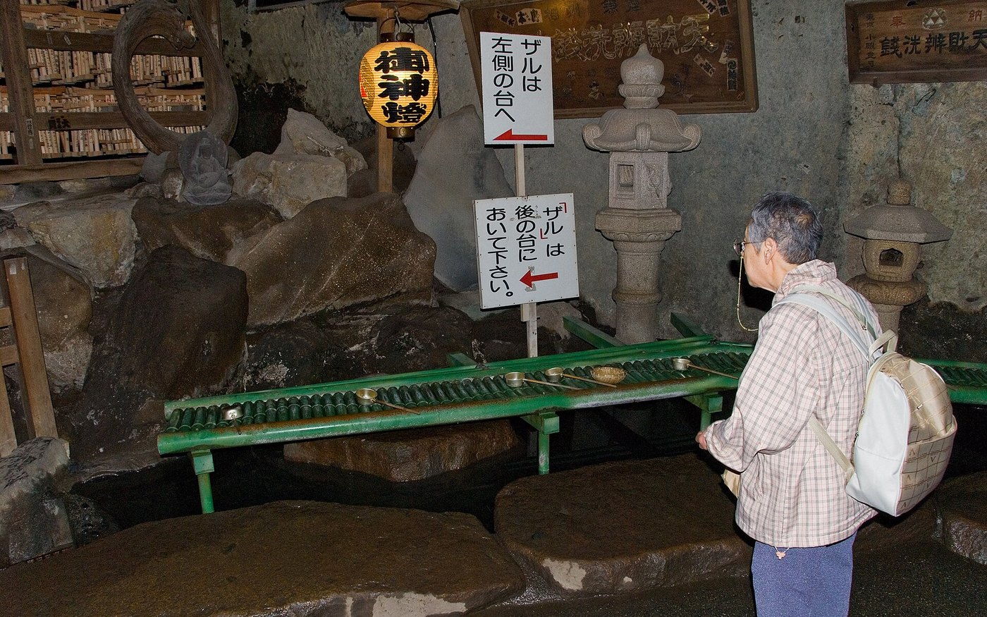 The washing stands at Zeniarai Benzaiten, with the basket rack, ladles and the shrine's signs