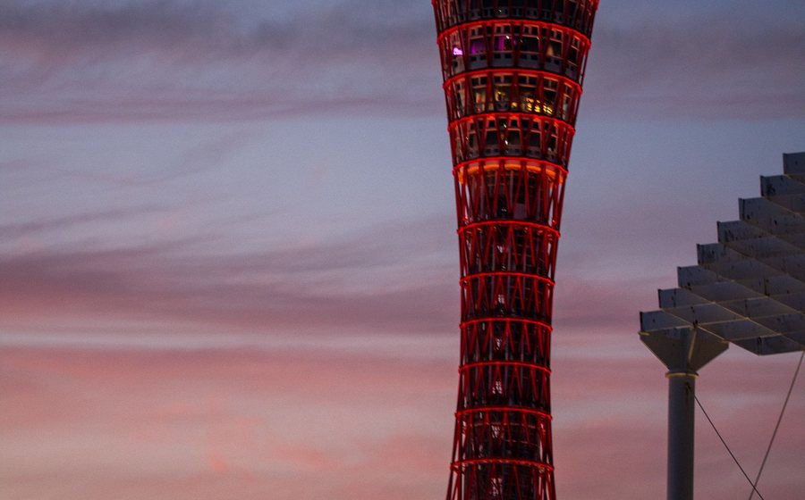 Kobe Port Tower lit up at dusk, seen across the water of Meriken Park