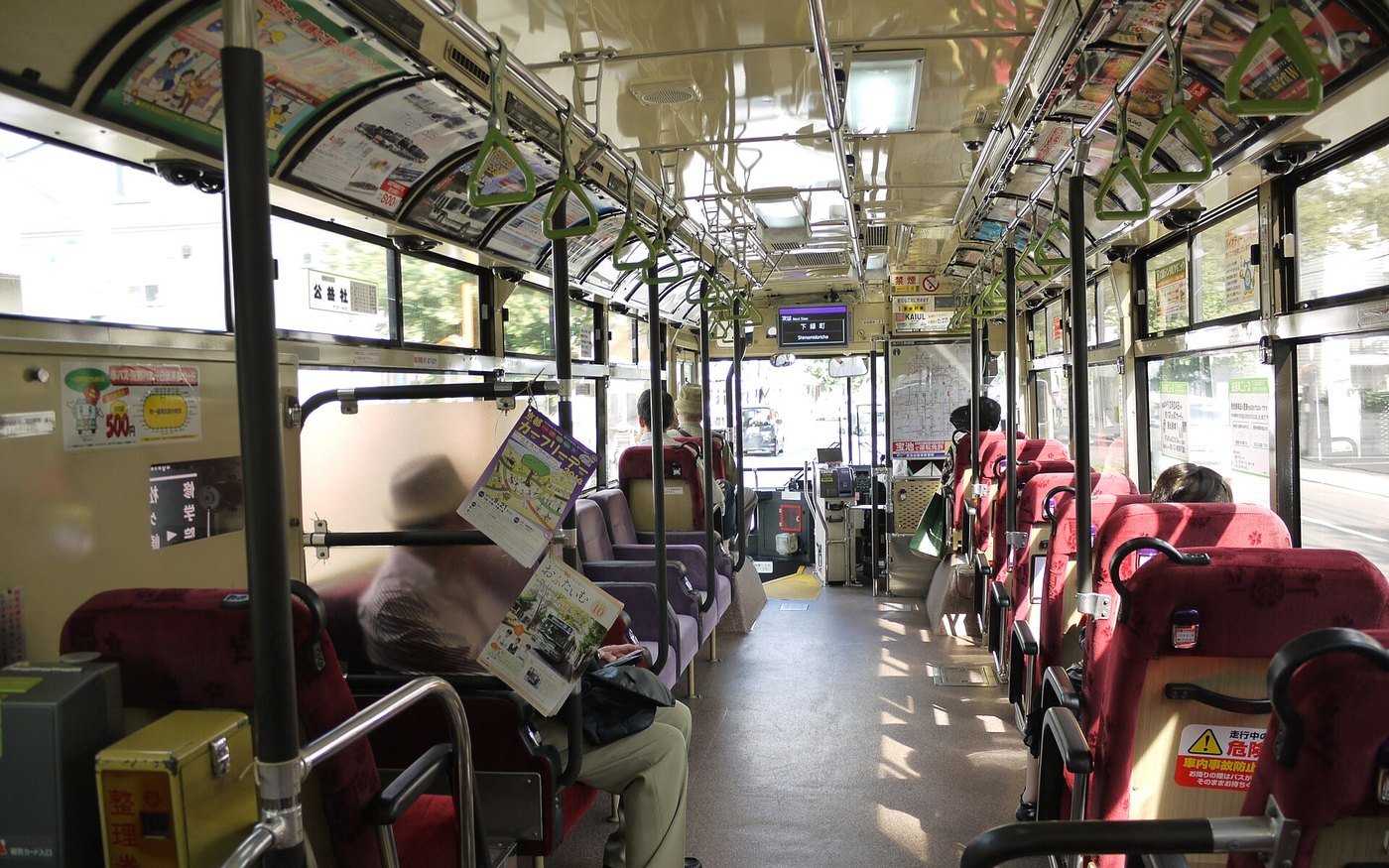 The interior of a Kyoto city bus with passengers seated and standing