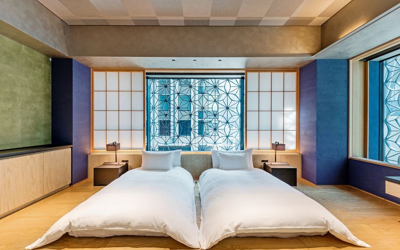 A modern Japanese hotel room with two single beds on a wooden platform