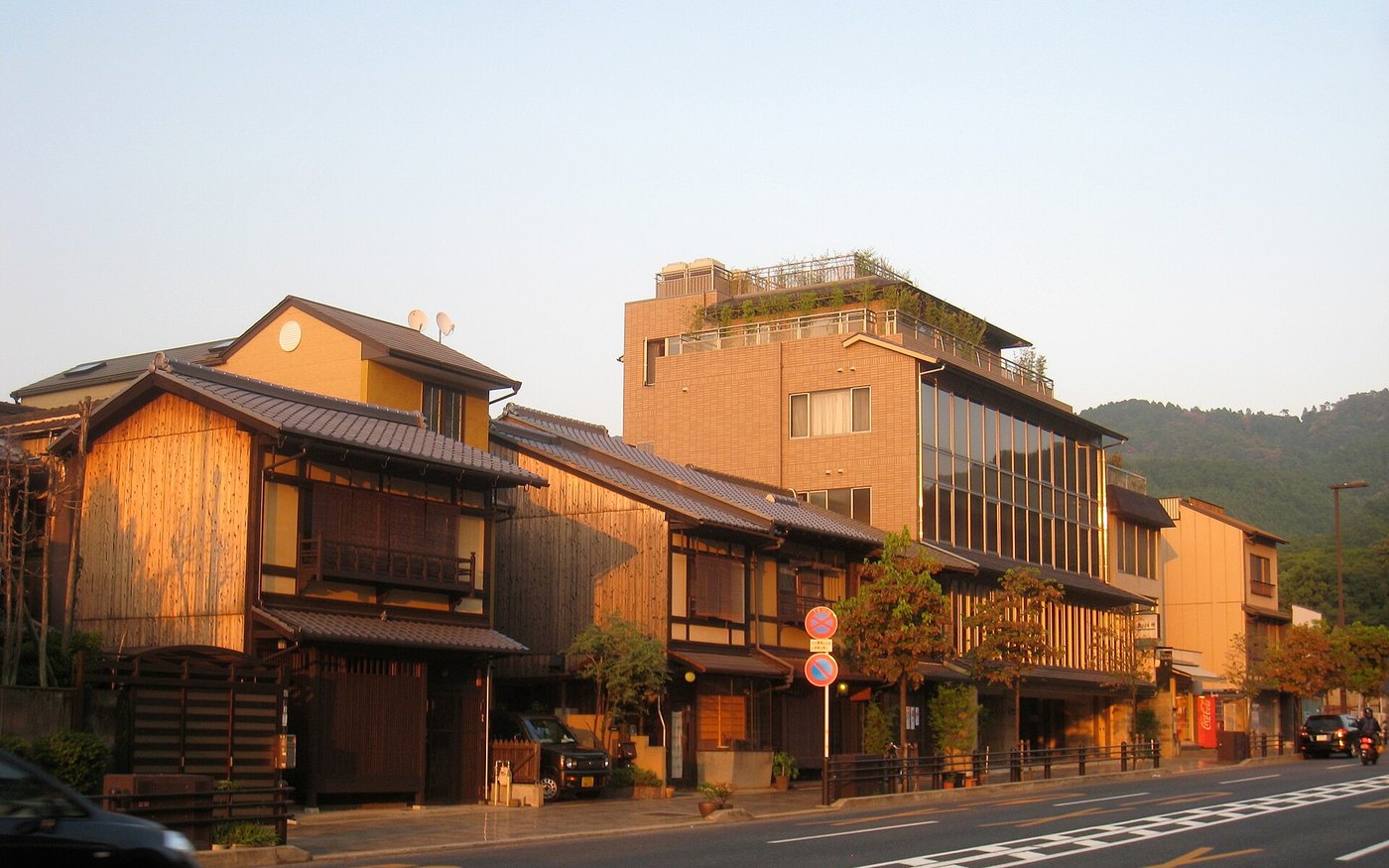 A row of traditional machiya townhouses with wooden lattices along a Kyoto street