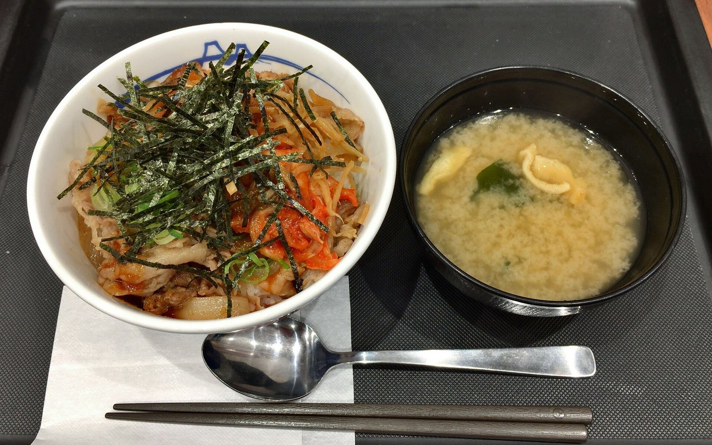 A beef bibimbap bowl at Matsuya with vegetables, egg and shredded nori on rice, with soup beside it