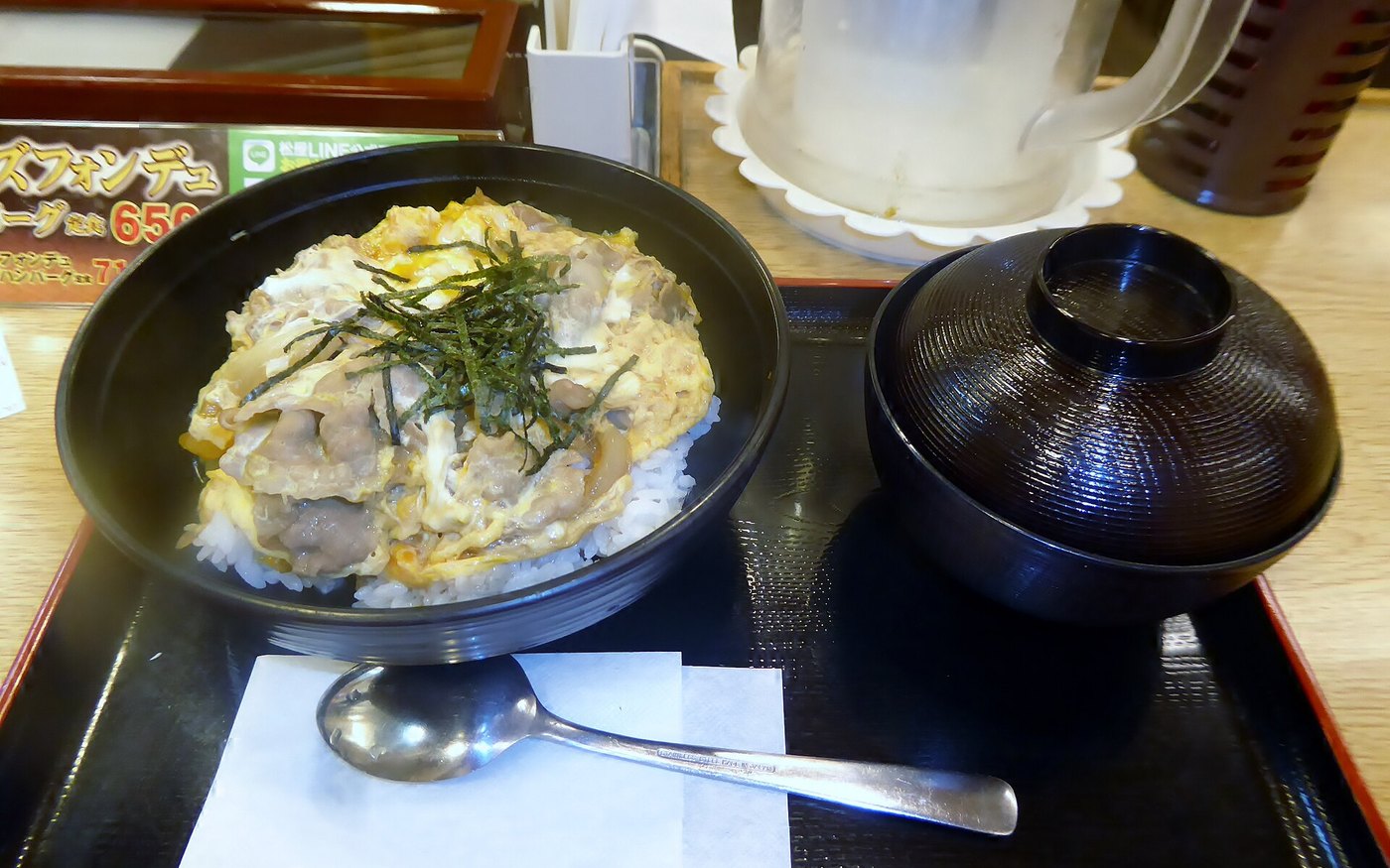A bowl of rice with beef and a soft egg at Matsuya, with a lidded bowl of miso soup on the tray