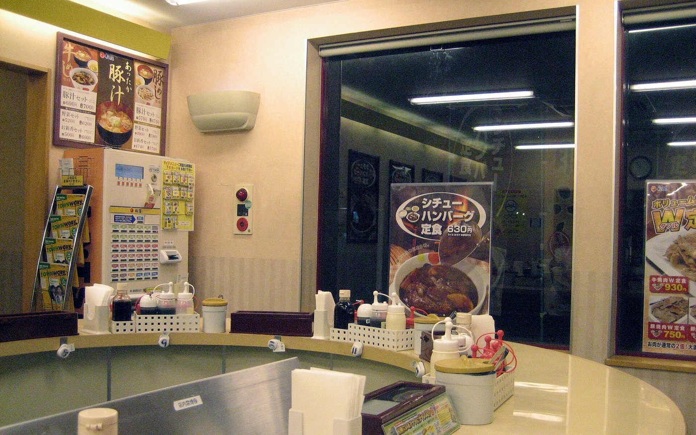 The inside of a Matsuya branch, the white ticket machine with its button grid standing behind the counter