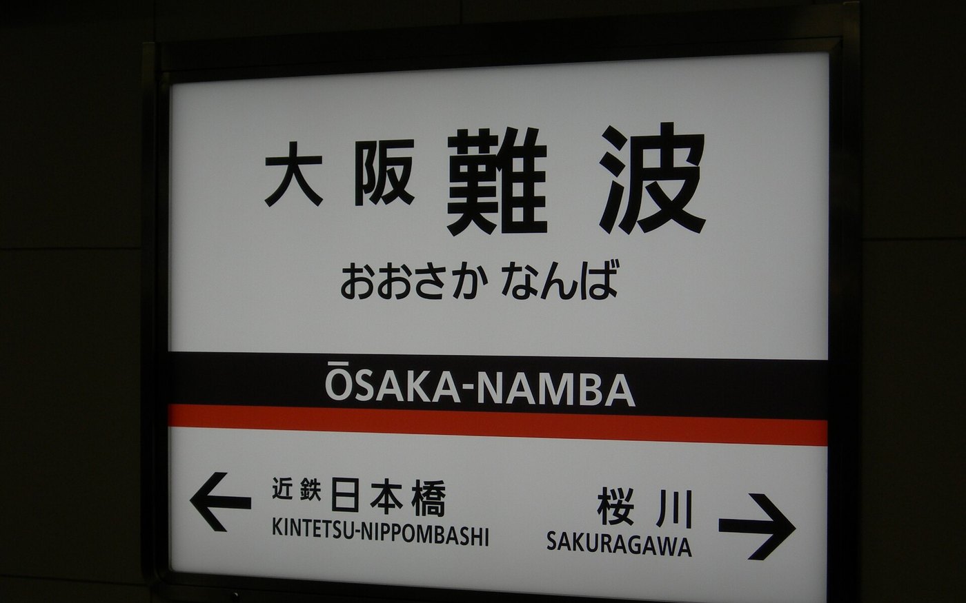 The Osaka-Namba station name sign mounted on a platform wall
