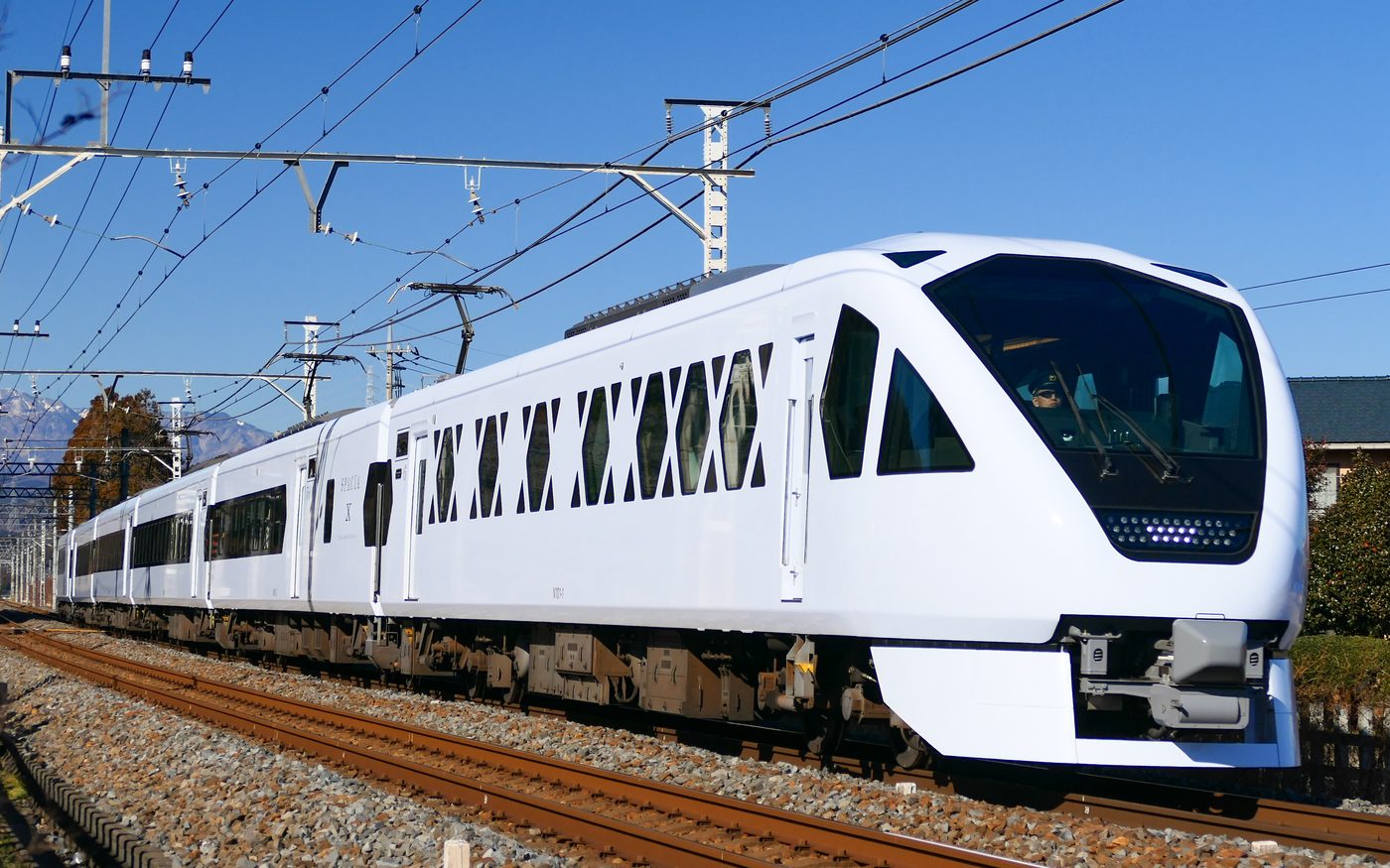 A white SPACIA X limited express with a black windshield band and X-shaped side windows, standing at a platform