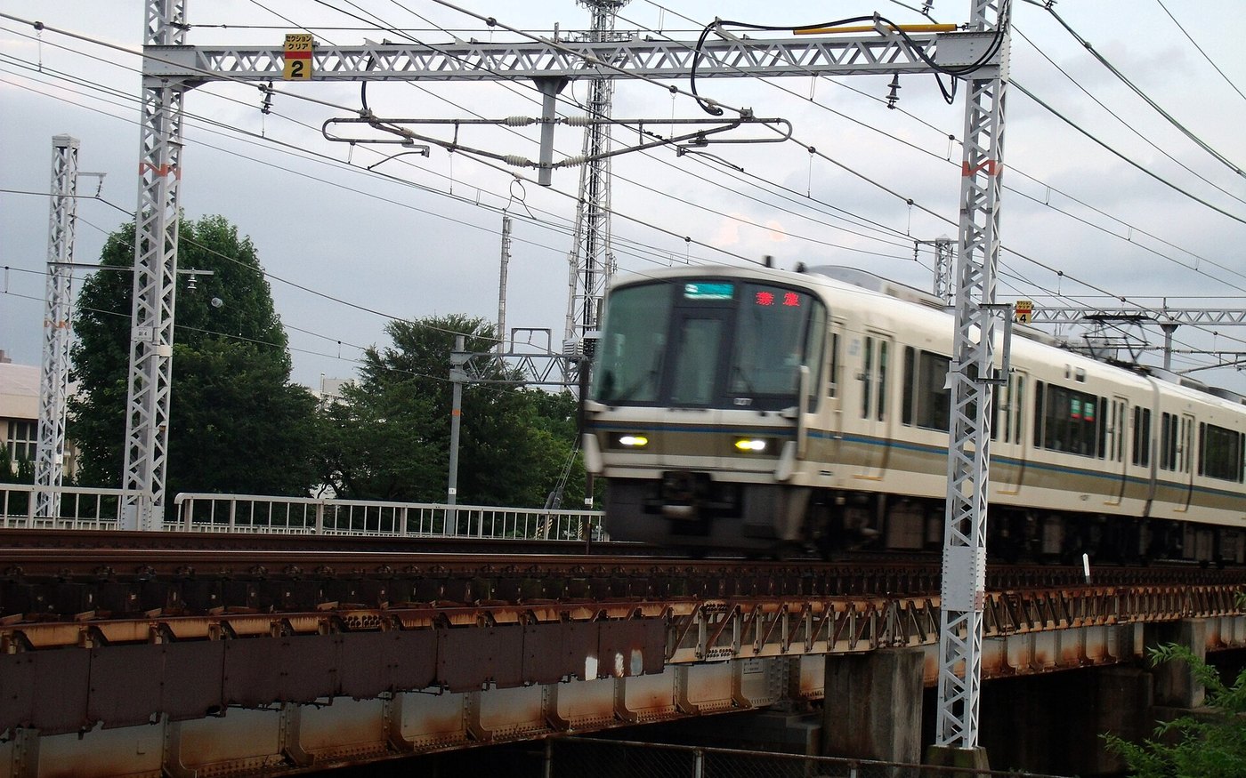 A JR commuter train crossing a steel bridge on the Osaka Loop Line
