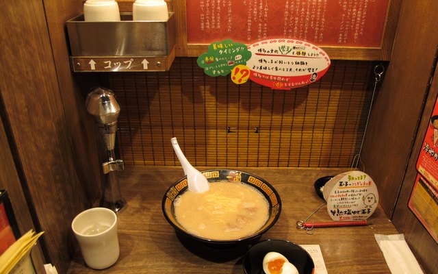A bowl of tonkotsu ramen on the counter of a partitioned Ichiran seat