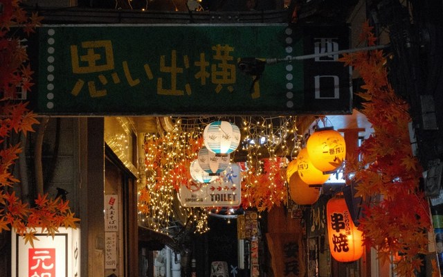 The Omoide Yokocho entrance in Shinjuku at night, lanterns strung over the alley