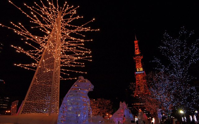 Lit ice sculptures and illuminated trees with the Sapporo TV Tower behind