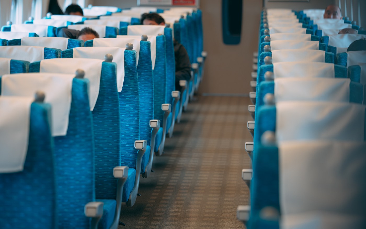 Rows of blue ordinary-class seats and an empty aisle inside a Shinkansen carriage
