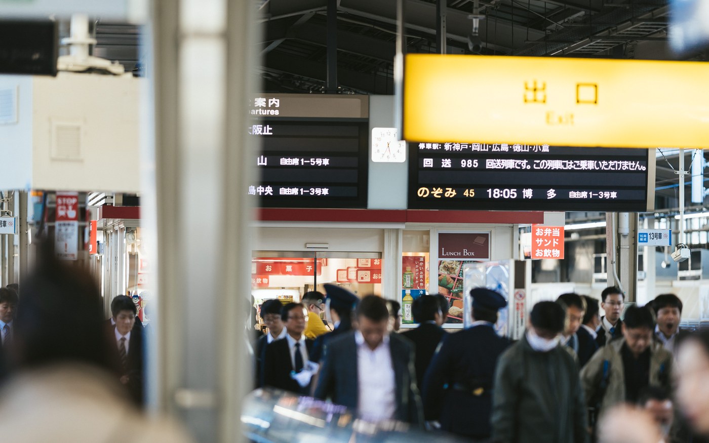 Passengers on a Shinkansen platform looking up at a departure board