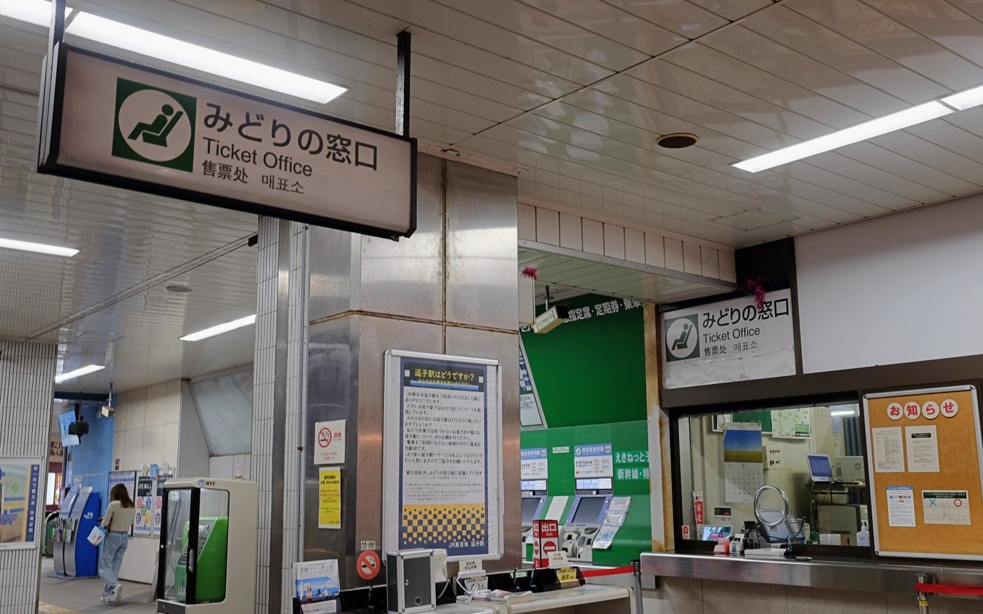 A green ticket-office sign reading みどりの窓口, Ticket Office, 售票处 and 매표소 above a service window and ticket machines