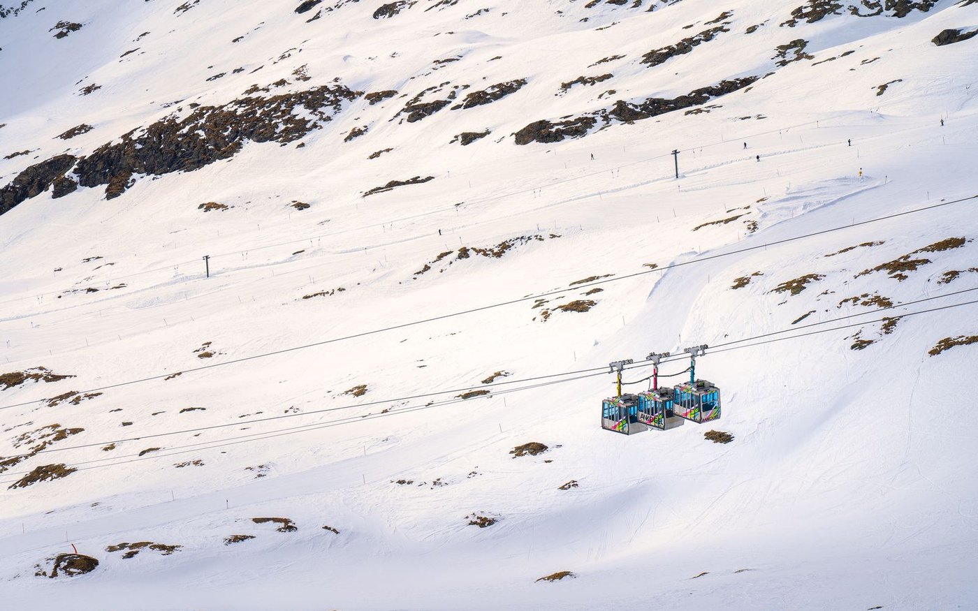 A blue gondola cabin on its cable above a snowy slope