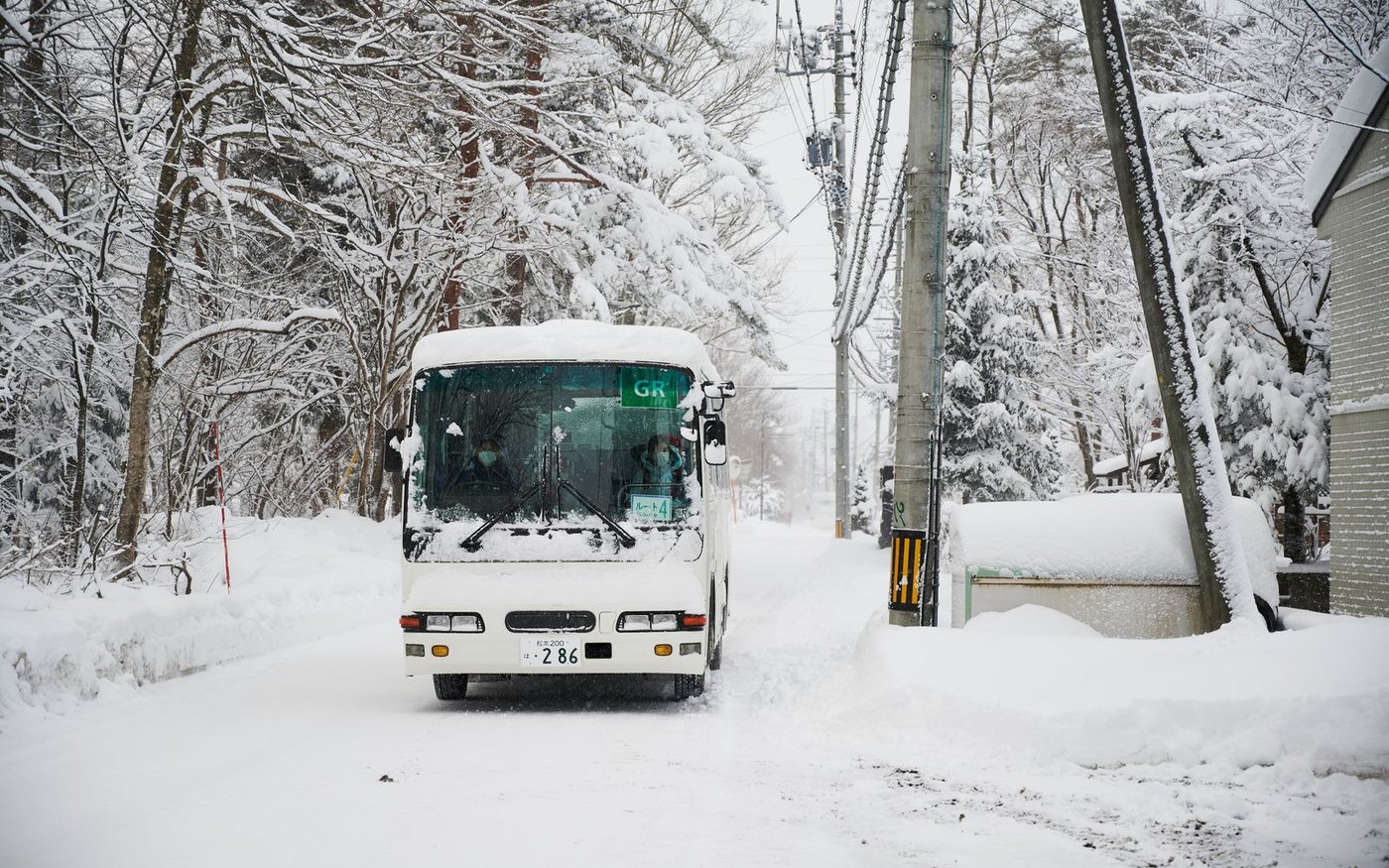 A white bus on a snow-covered road between snowy trees