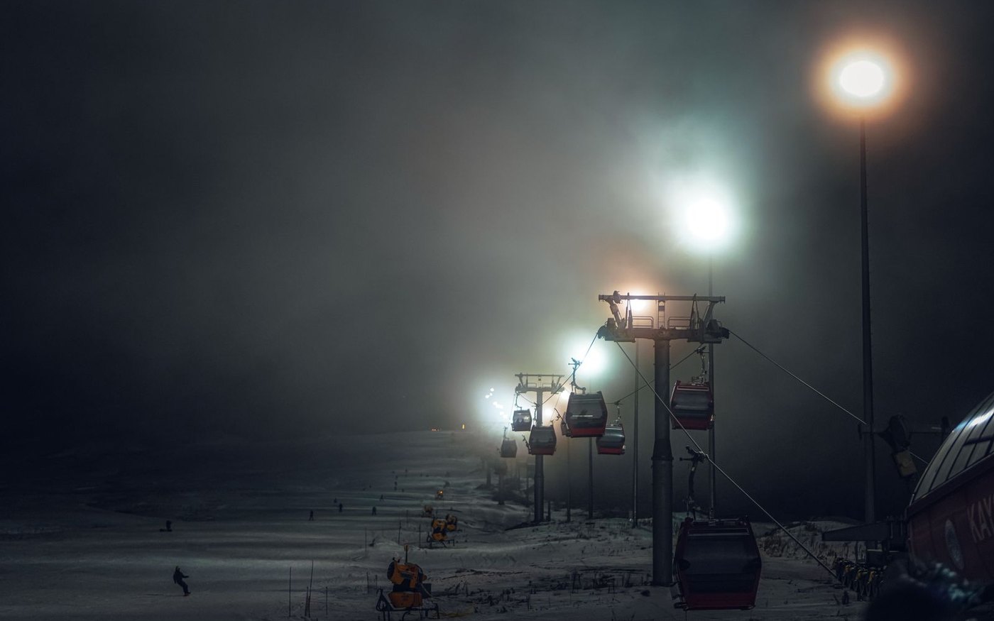 A chairlift lit at night on a snowy slope