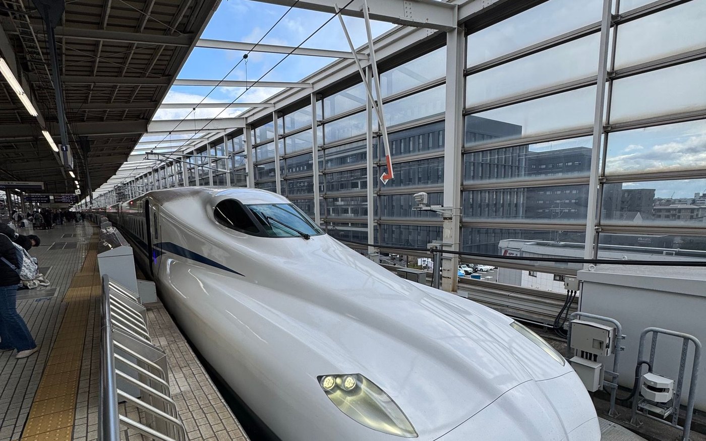 A Shinkansen train at a station platform under a steel canopy